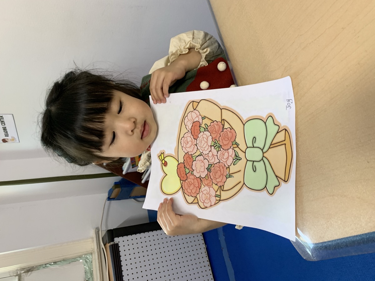 小女孩展示亲手完成的康乃馨花束贴画手工作品
