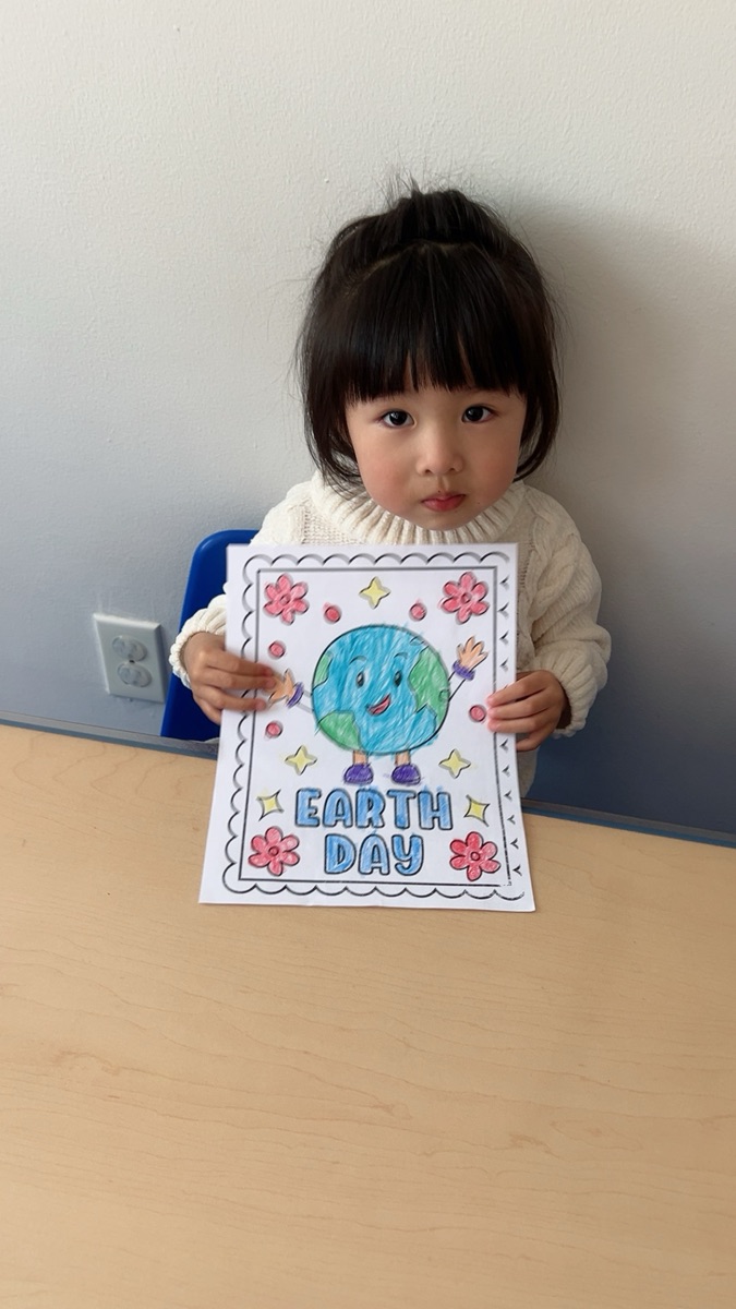 小女孩展示她涂色完成的Earth Day地球主题画
