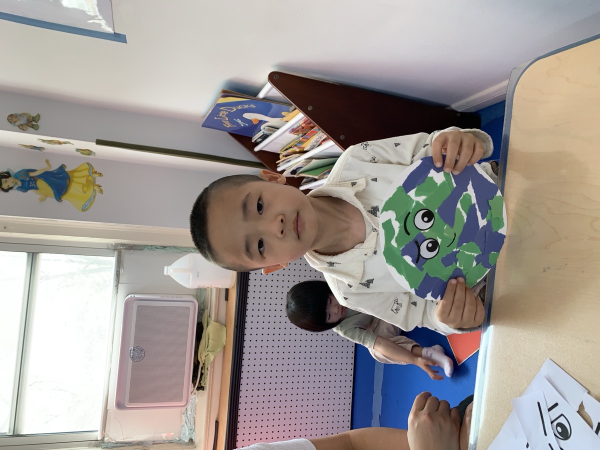 小男孩展示亲手制作的地球日蓝绿撕贴地球作品